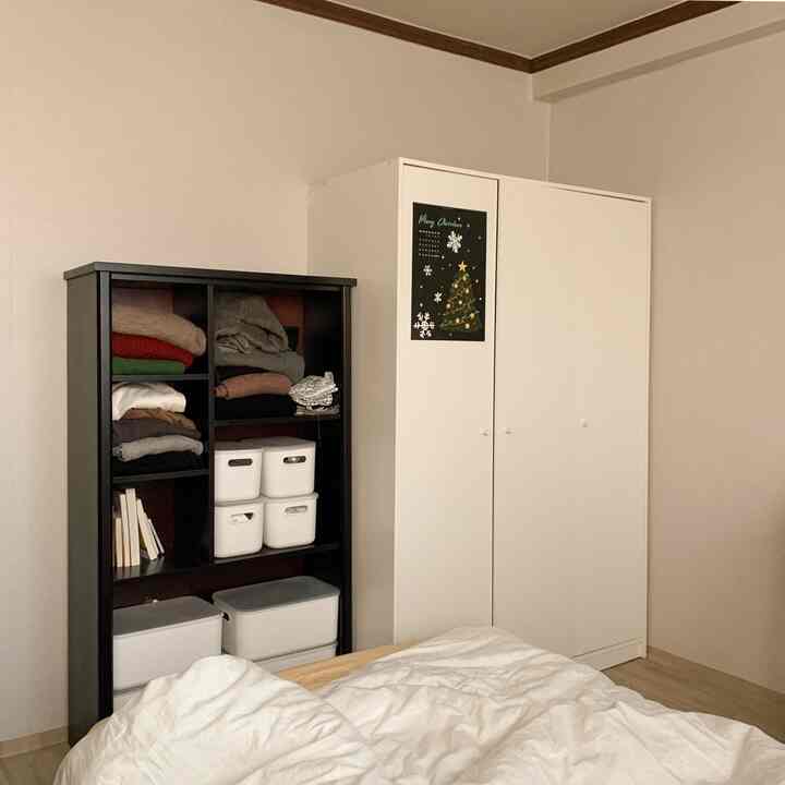 ホワイトとブラウンの落ち着いた色調の寝室、整頓されたクローゼットと収納棚が配置された雰囲気のあるインテリア