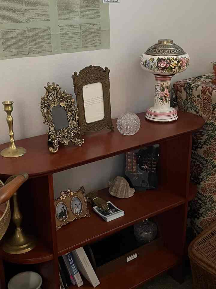 落ち着いたブラウンのヴィンテージ風キャビネットに多様なアンティークのオブジェや装飾品が並ぶ寝室の雰囲気のあるインテリア