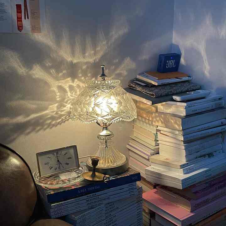 白とゴールドの色調の落ち着いた読書スペース、壁に映る光と積まれた本が調和するクラシックなインテリア