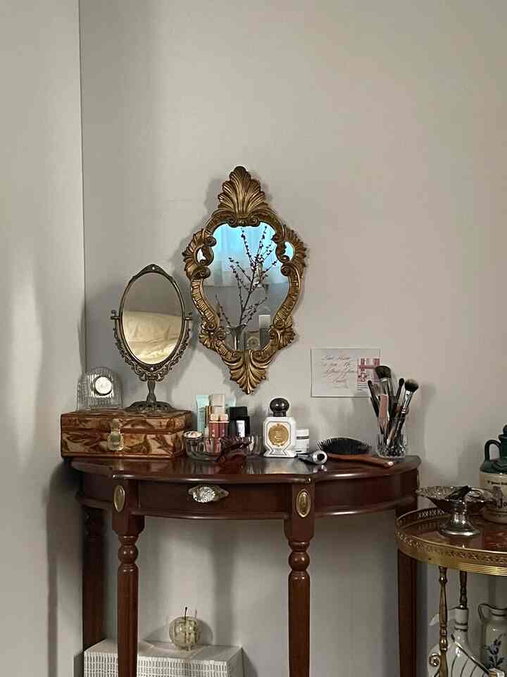 ブラウンの木調家具とゴールドの装飾的な鏡がある居心地の良い化粧台スペース