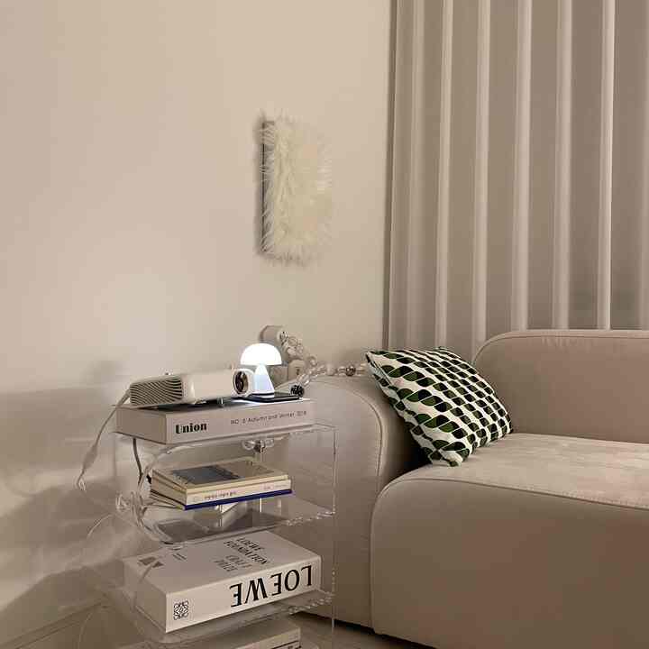 白と透明の素材が調和するリビング、ベージュのソファとパターン柄クッション、LEDマッシュルームランプが雰囲気のある空間を演出