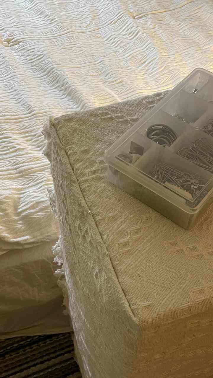 ホワイトとベージュのファブリックで覆われた本棚があるボヘミアンスタイルのリビング、温かみのある落ち着いた雰囲気のインテリア