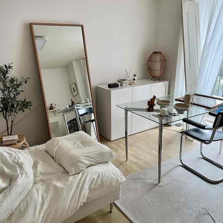 白とナチュラルカラーのリビング、ベッドとガラス製ダイニングテーブルが配置されたシンプルで清潔感のあるインテリア