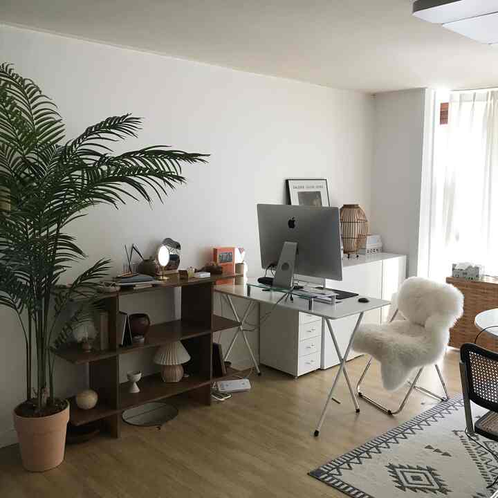 白と木目調の調和が取れたホームオフィス空間、コンピュータのあるデスクとダイニングチェア、本棚が配置されたモダンなワークスペース