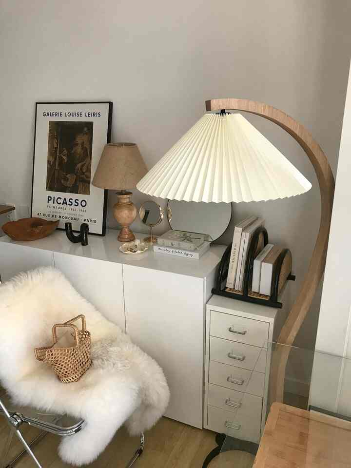 白と木目調の調和がとれたダイニングルーム、キャビネットとフロアランプが配置された温かみのある空間