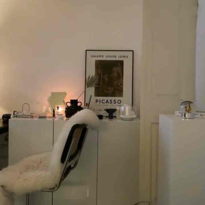 ホワイトとナチュラルカラーの寝室、シンプルな収納キャビネットとピカソの額縁が配置された落ち着いた雰囲気のインテリア