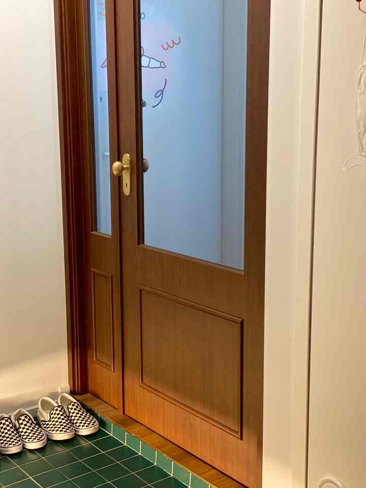 ディープグリーンのタイル床とウォールナット色の間仕切りが配置された玄関スペース