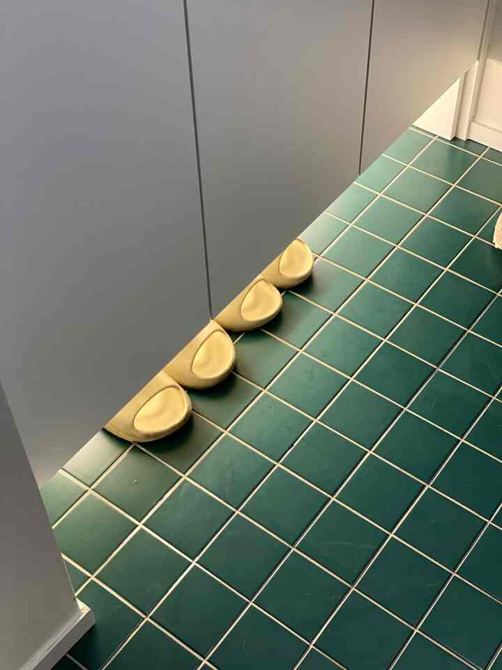 ダークグリーンのタイル床と下に黄色い靴が並ぶすっきりとした玄関スペース