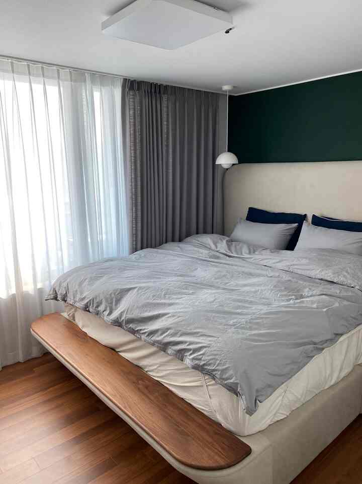 グレーとナチュラルカラーの調和のとれた寝室に、ウォールナットの木製フレームが特徴のスーパキングサイズのベッドが配置され、ホテルライクな上質な雰囲気を醸し出している。