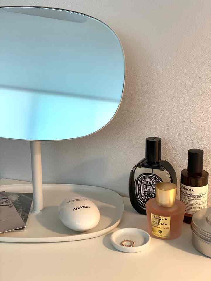 ナチュラルな色調とホワイトのトーンのドレッシングルームの化粧台に香水と小さなトレイが並べられた清潔感のあるインテリア