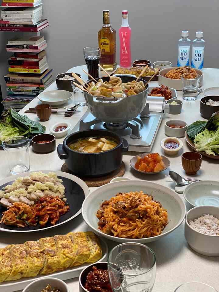 白い壁とダイニングテーブルのあるダイニングルーム、ガスバーナーと韓国料理が並ぶ雰囲気のあるホームパーティー空間