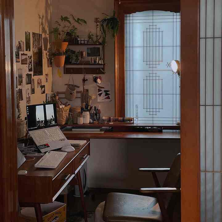 温かみのある木目調と観葉植物が調和したコンパクトなホームオフィス、壁のデコレーションが雰囲気を高めるインテリア