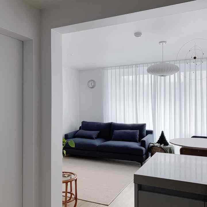 白とネイビーの色調のリビング、濃いネイビーのソファと白いペンダントライトが配置された居心地の良い空間