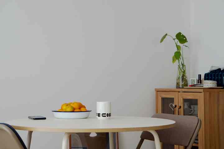 白とベージュのトーンでまとめられたシンプルなダイニング、円形のテーブルと椅子が配置された落ち着いた空間