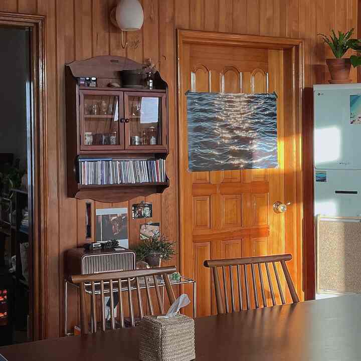 温かみのある木目調のダイニング、木製のテーブルと椅子、壁の装飾と自然光が落ち着いた雰囲気を演出した空間