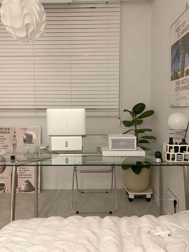 白とグレーのモノトーン寝室、ガラスデスクとノートパソコンが配置されたモダンなホームオフィス空間