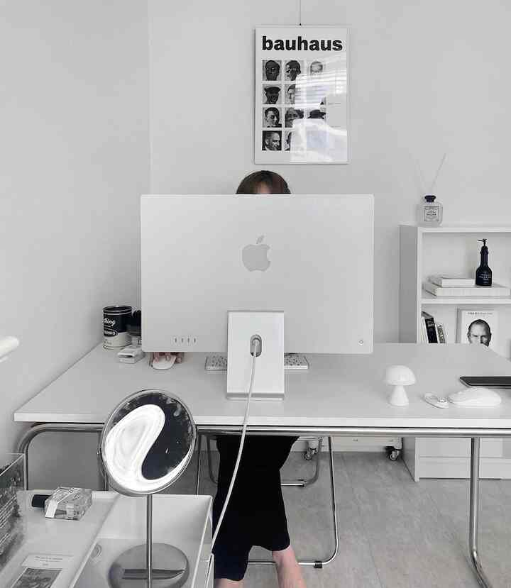 ホワイトトーンのホームオフィス、大きな白いデスクとコンピューター、シンプルなインテリアが印象的な空間