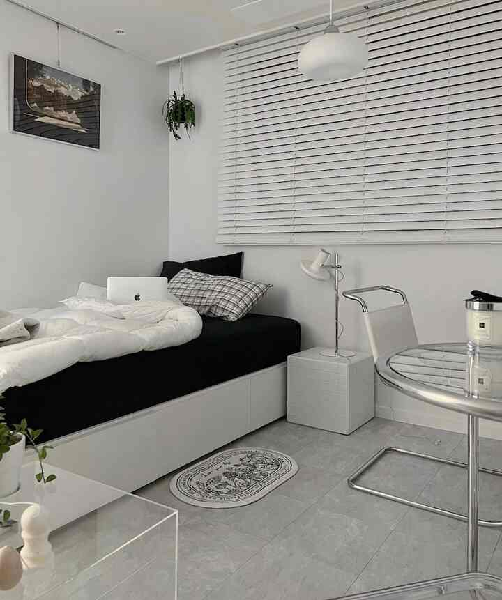白と黒のトーンの寝室、シングルベッドと白いブラインドが配置されたモダンでミニマルな印象的な空間