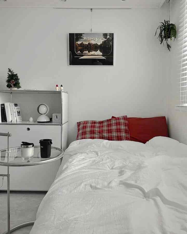 白と赤のトーンの寝室、シンプルな収納棚と枕が配置された雰囲気のある空間