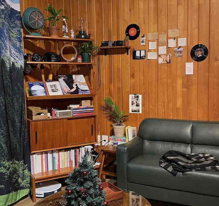 暖かい木目調の壁と緑のソファが配置されたナチュラルスタイルのリビング