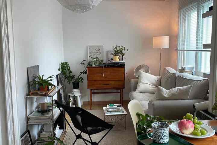 白い壁と木目調家具が調和したコンパクトなリビング、ライトグレーのソファとフロアランプが落ち着いた雰囲気を演出