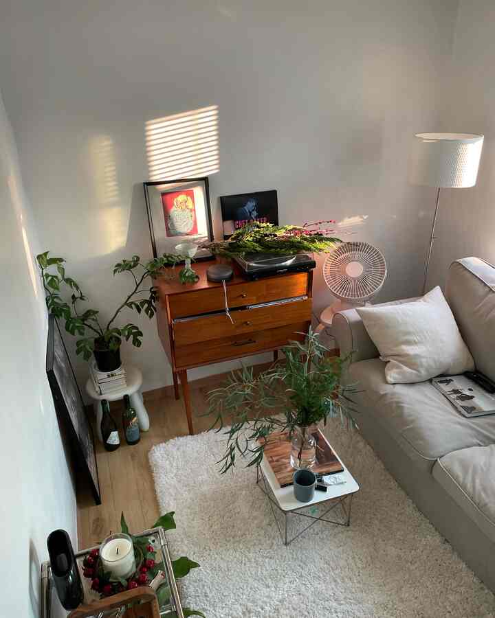 白とナチュラルブラウンのトーンのリビング、ベージュのソファとラグ、木製コンソールと植物が配置された雰囲気のあるインテリア