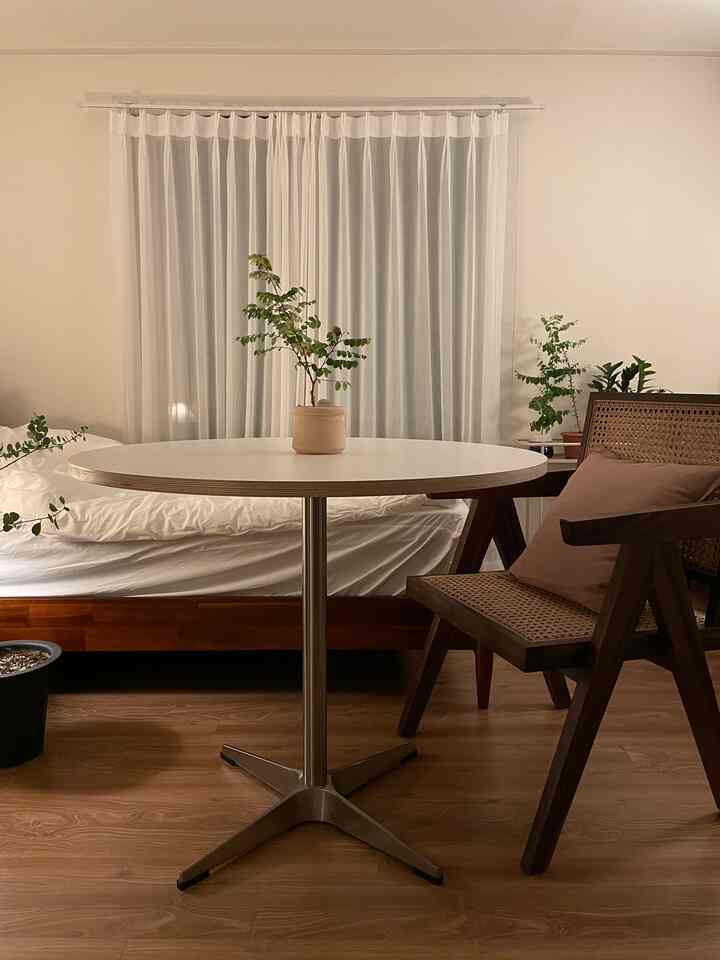 柔らかなベージュと木目調の寝室、白いダイニングテーブルとラタンチェアが配置された自然で落ち着いた雰囲気のインテリア