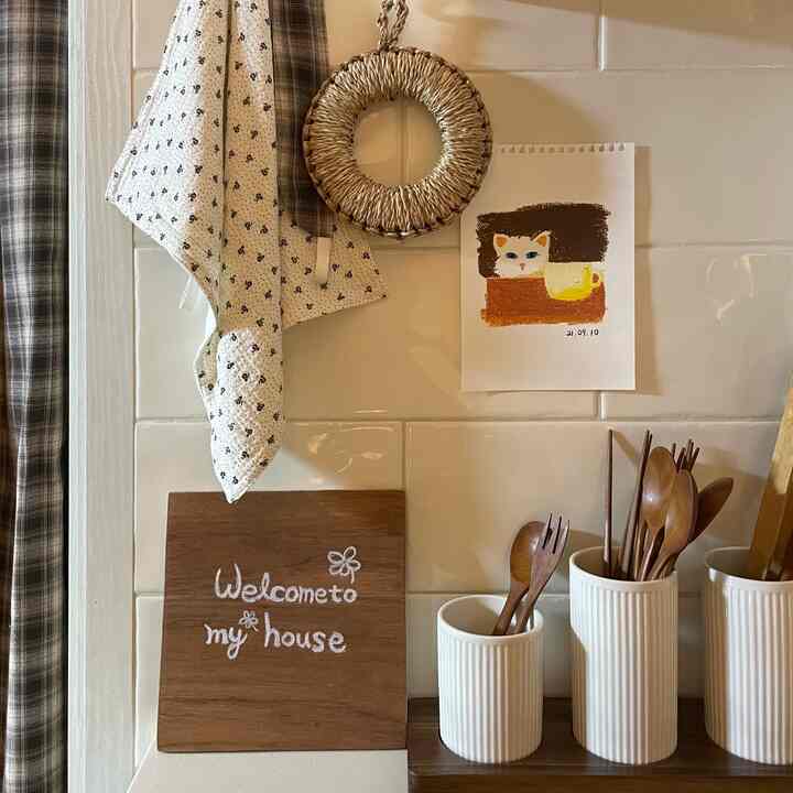 ウッドトーンと白いタイル壁のキッチン空間、木製カトラリーセットと小さな装飾品が配置された雰囲気のあるインテリア