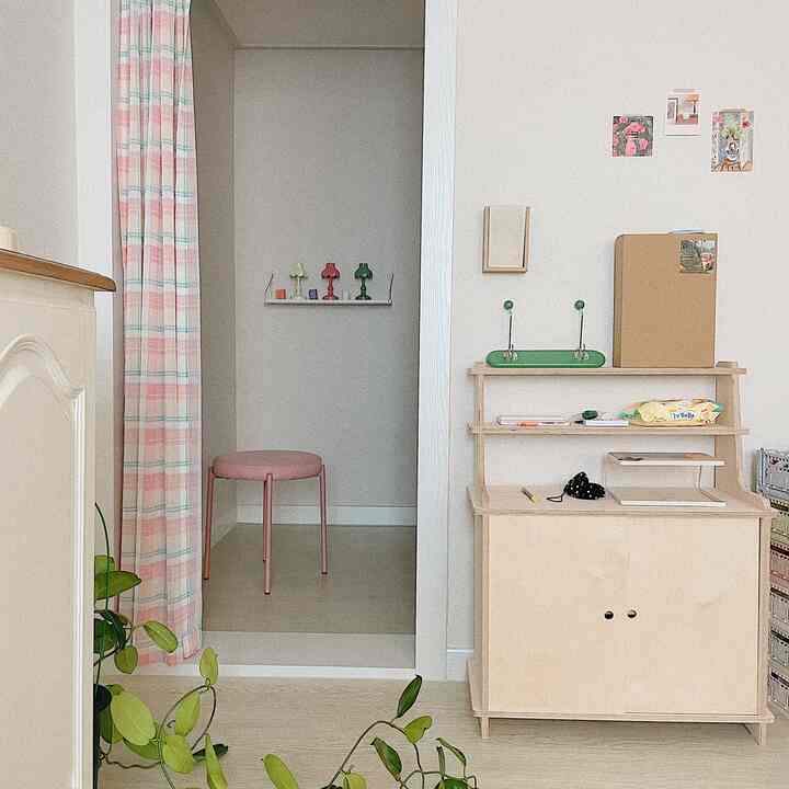 ピンクとミントのストライプカーテンと明るい木目調の収納があるナチュラルな玄関スペース