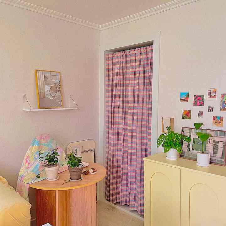 黄色と白の色調のリビング、丸いダイニングテーブルとカーテン、複数の植物が配置された雰囲気のあるインテリア