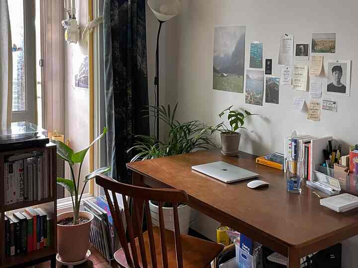 ブラウンの木製デスクと椅子、白い壁と植物が配置された居心地の良いホームオフィス