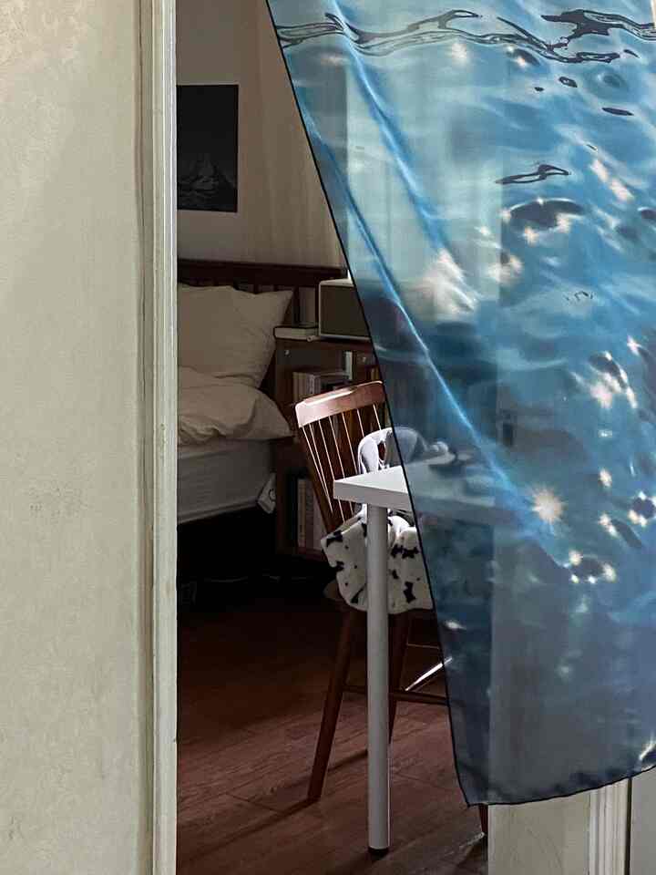 ブラウンの木目調と白を基調とした寝室とダイニングチェアが配置された居心地の良い小さな部屋