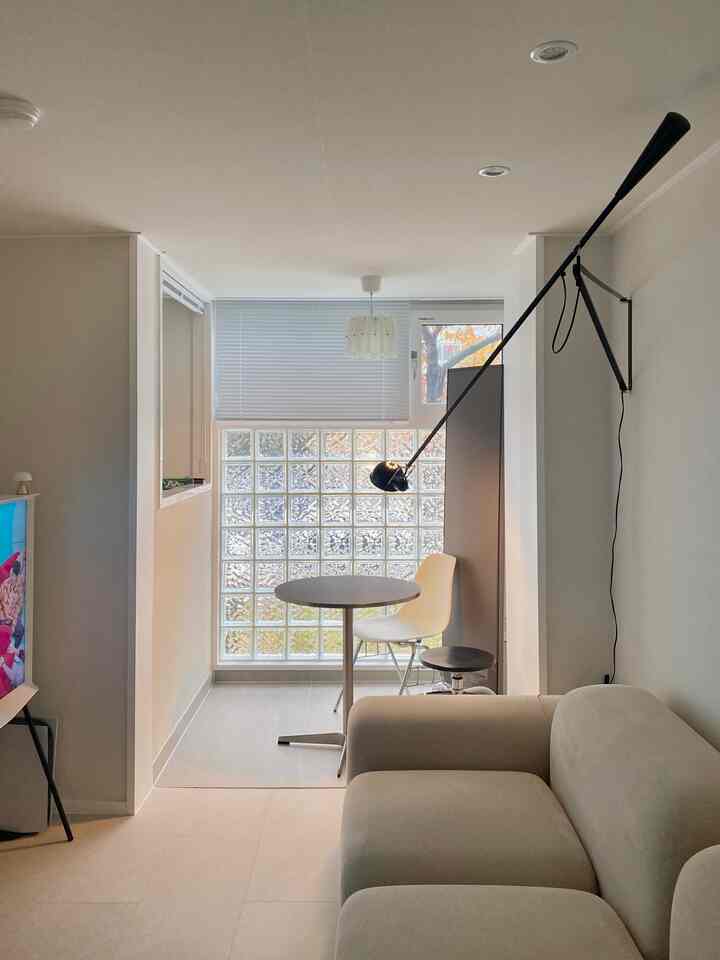 ホワイトとブラックのトーンの狭いベランダ空間、丸テーブルとソファが配置されたシンプルで清潔なインテリア