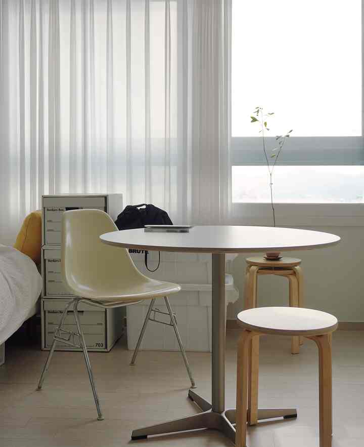 ナチュラルカラーの寝室空間、大きな窓の前に丸テーブルと椅子が配置された雰囲気のあるインテリア