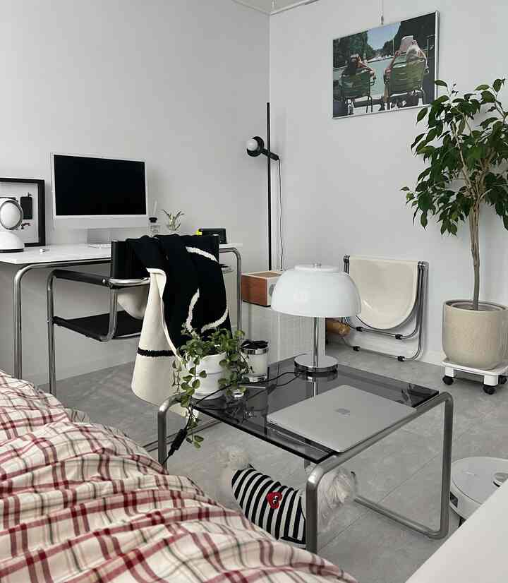 白と黒のトーンが特徴のコンパクトなホームオフィス、机とコーヒーテーブル、ペットの犬がいるシンプルモダンなインテリア