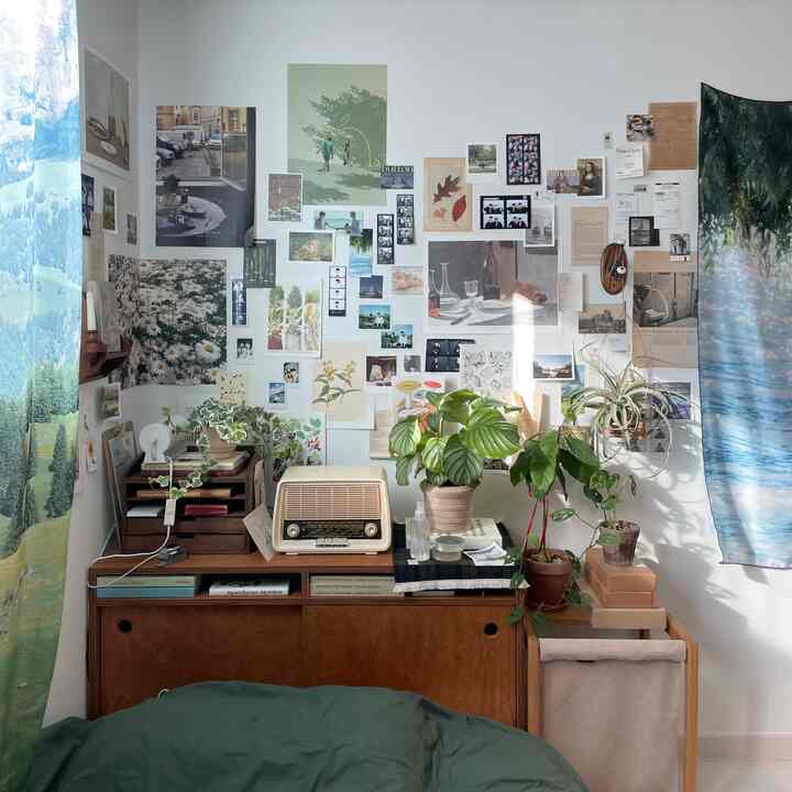 ナチュラルな色調の寝室、ベッドの頭部に配置されたヴィンテージラジオと植物、多彩なウォールアートが調和した印象的な空間