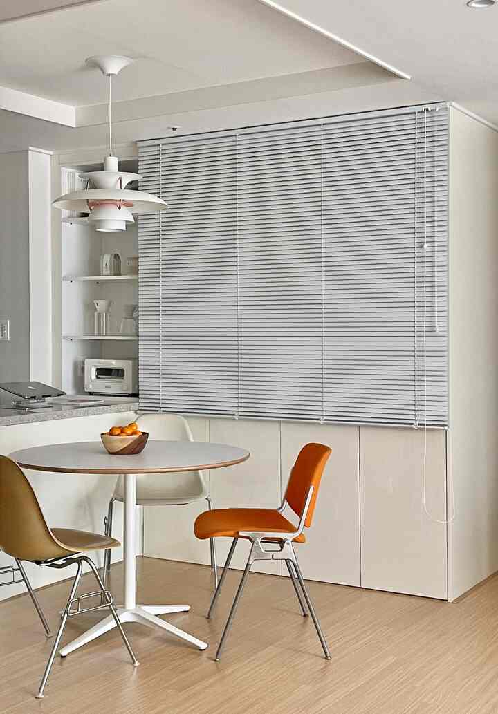 白と木目調のダイニング空間、丸テーブルとカラフルな椅子が調和する印象的なモダンインテリア