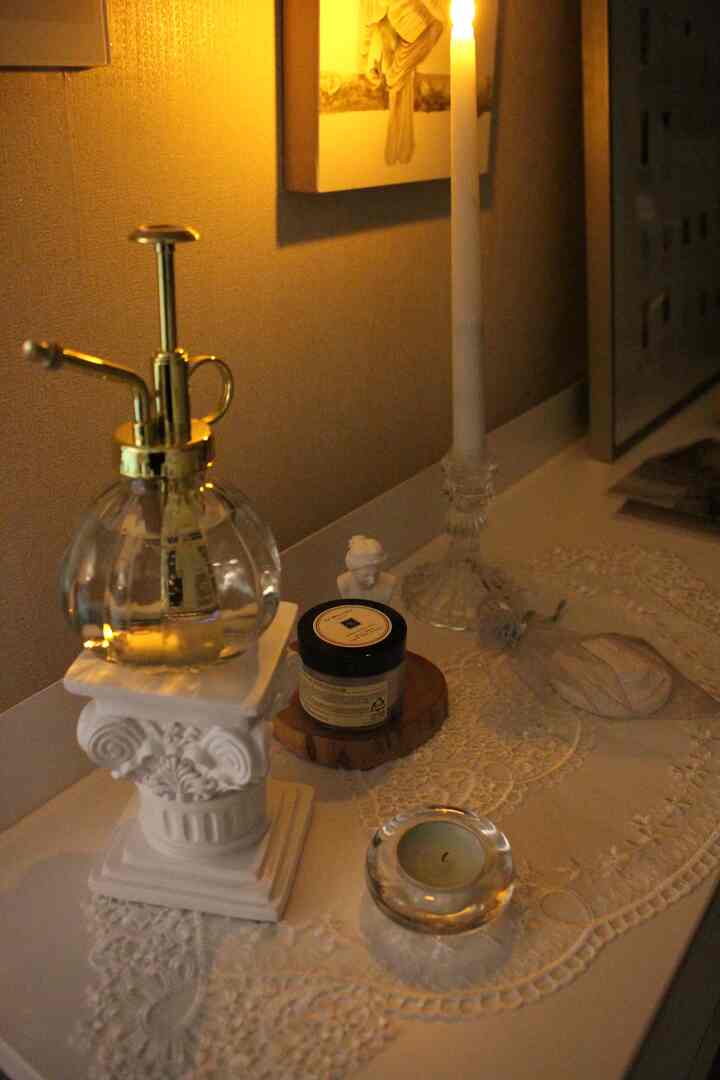 温かみのあるゴールドとクラシックな白のトーンで飾られた、小さなテーブルの上に置かれたアンティークのオブジェとキャンドルのある雰囲気のあるインテリア