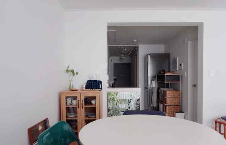 ホワイトと木目調が調和したキッチン、シンプルな収納家具とステンレスの冷蔵庫が配置されたモダンな雰囲気のインテリア