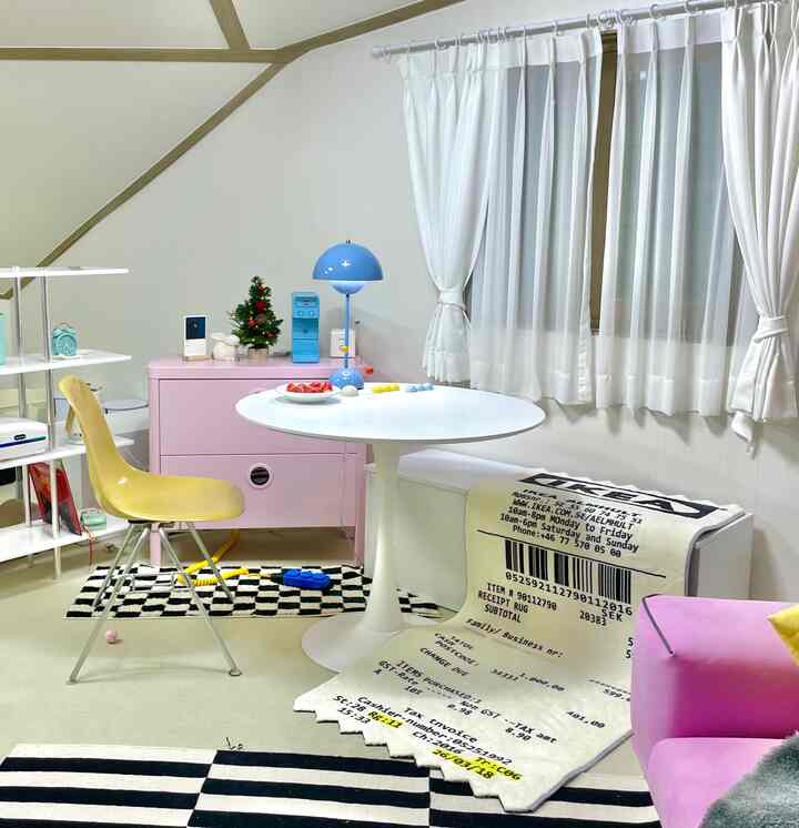 白とピンクのトーンの小さなリビング、丸いダイニングテーブルと棚、引き出しが配置された雰囲気のあるインテリア