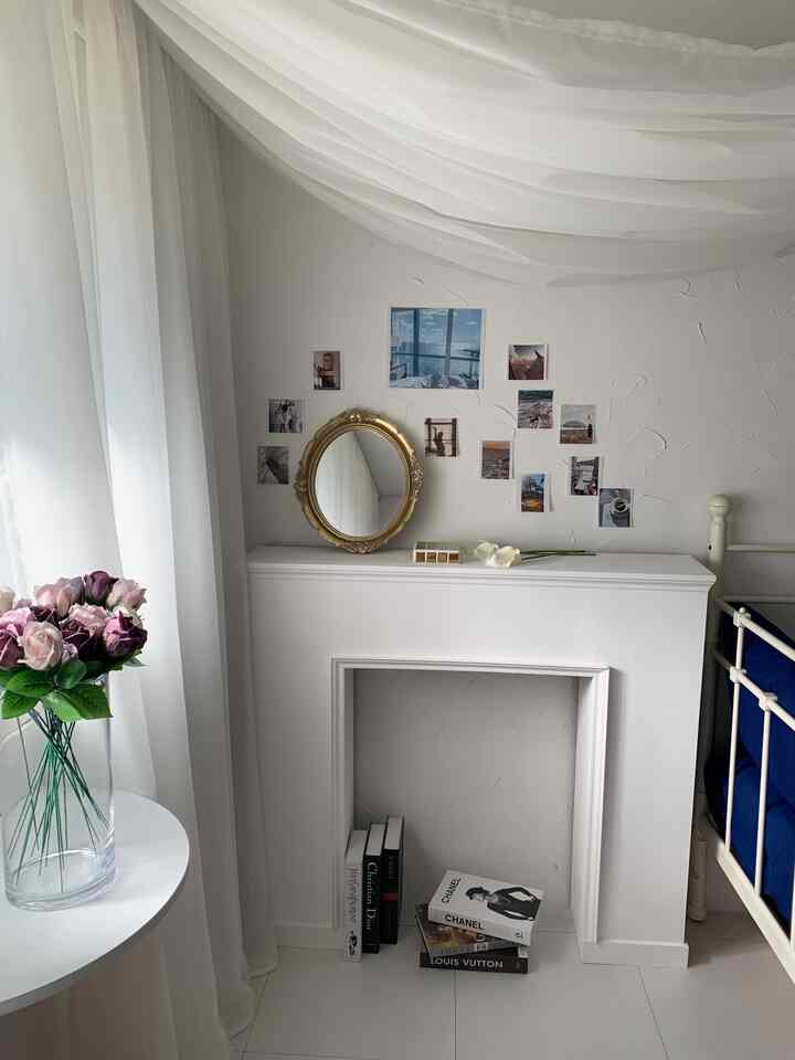 白を基調とした寝室の空間、ゴールドの装飾ミラーとコンソールテーブルが配置されたシンプルでナチュラルなインテリア