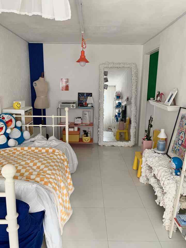 白と黄色のナチュラルモダンな一人用寝室。ドラえもんのぬいぐるみと大きな鏡が配置され、印象的で落ち着いた雰囲気のインテリア