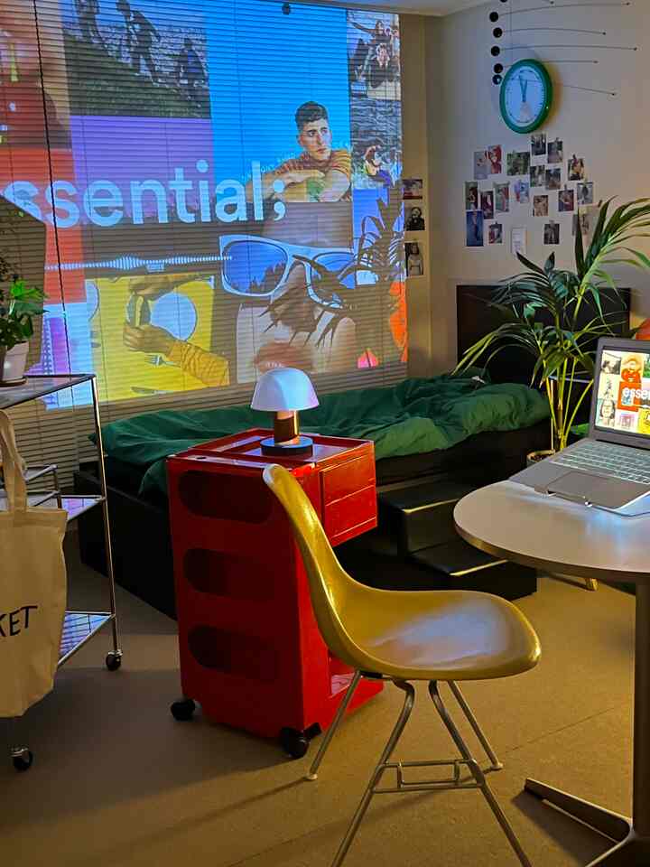 赤と黄色がアクセントの小さな一人暮らしの部屋、ソファベッドとノートパソコンのある在宅勤務スペース