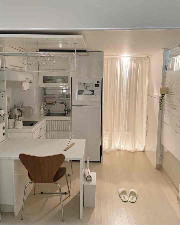 白とライトブラウンの色調の玄関とキッチン、カーテンで区切られた清潔で落ち着いた雰囲気のあるインテリア