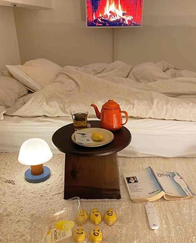 ベージュ色調の温かみのある寝室、小さな木製コーヒーテーブルとテーブルランプが配置された雰囲気のあるインテリア