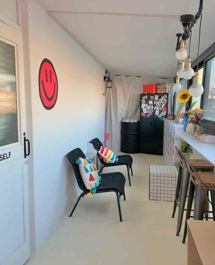 ホワイトとブラックのトーンで構成された縦長の狭い部屋、バースツールとモザイクタイルのテーブルが配置された雰囲気のあるおうちカフェ空間