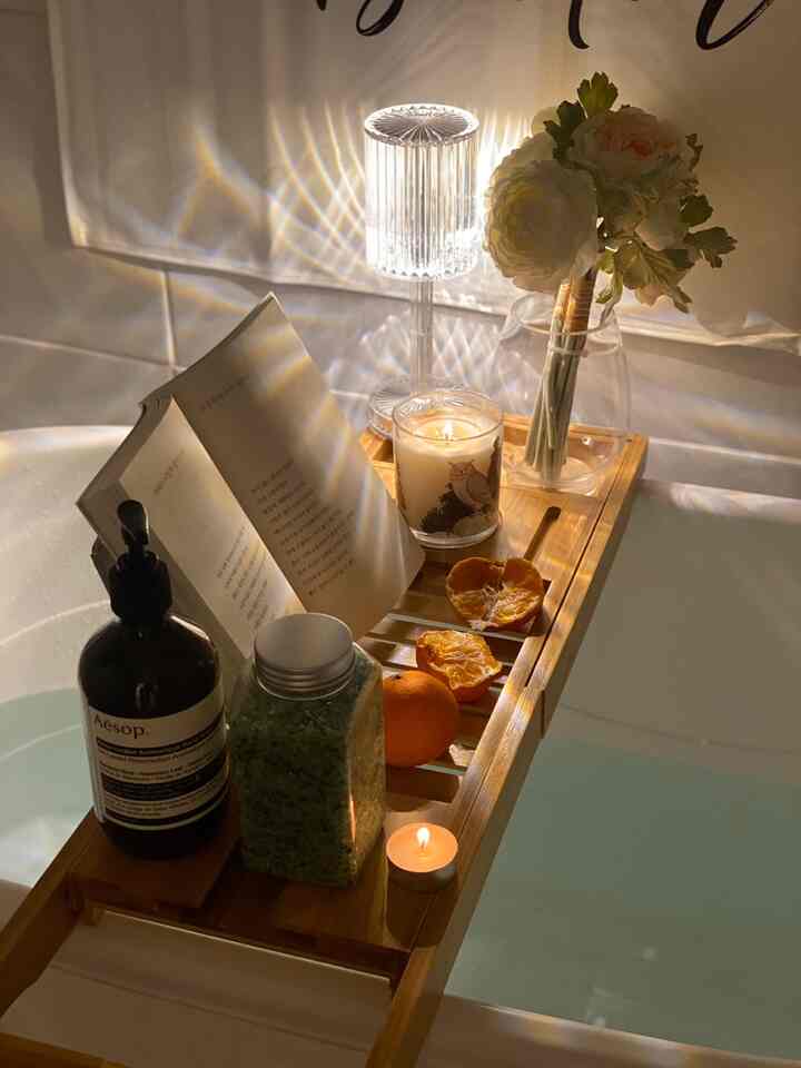 暖かみのある木目調と白を基調とした浴室、キャンドルや花瓶、本が置かれたバストレイが印象的な半身浴のリラクゼーション空間