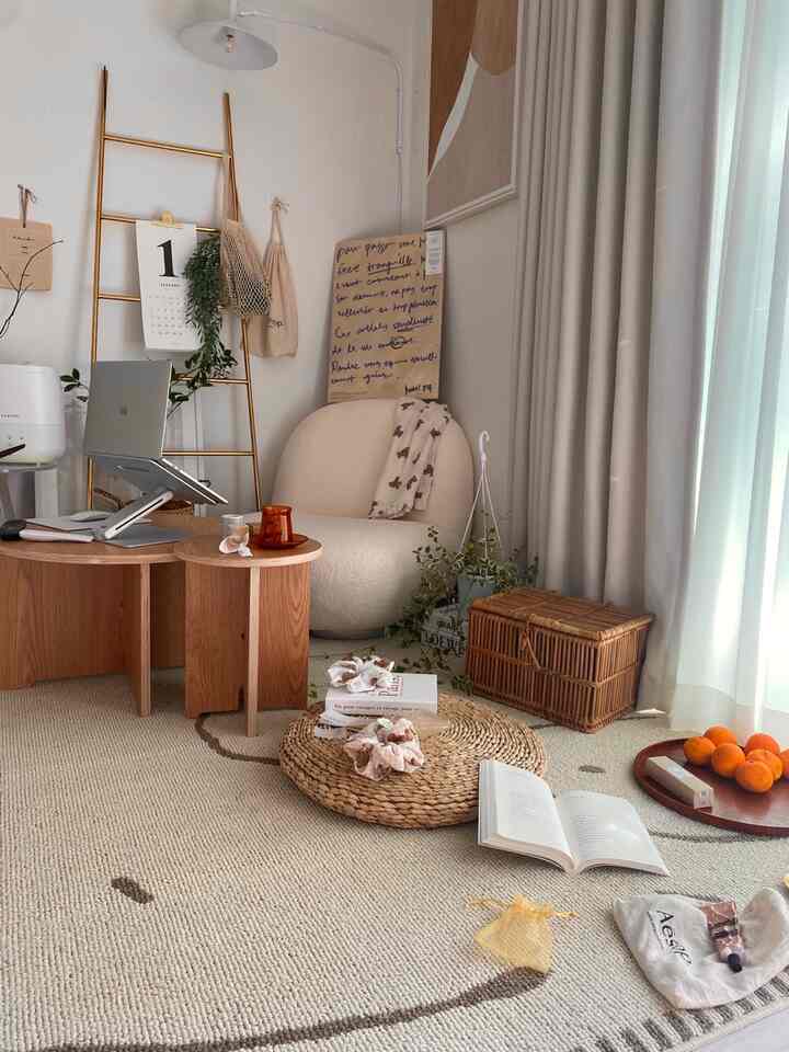 ナチュラルな色調のリビング隣接の空間、ラタンバスケットと木製サイドテーブル、クリーム色のアームチェアが配置された雰囲気のある読書空間