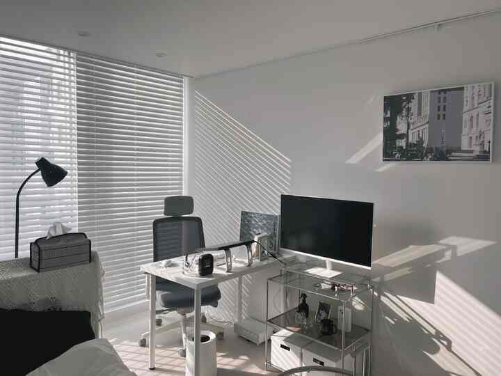 清潔感のあるホワイトトーンのホームオフィス、シンプルなデスクとオフィスチェア、モダンなモニタースタンドが配置された明るく整理された空間