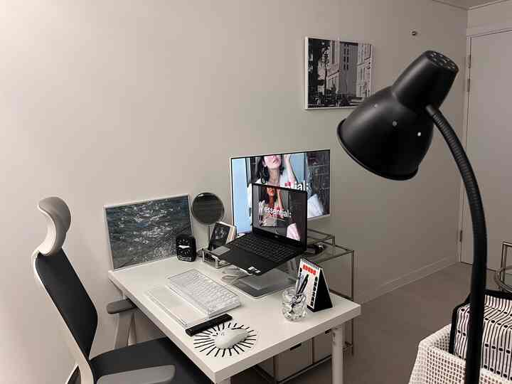 白と黒のモダンなホームオフィス、デスクとオフィスチェア、ノートパソコンとポスターが配置された清潔感のある作業空間